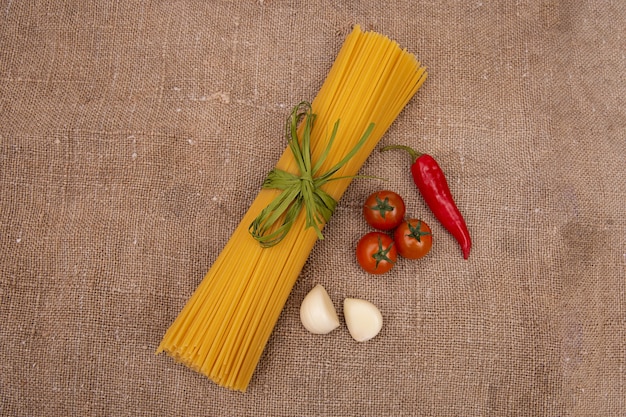 Rauwe Pasta met ingrediënten op linnen of jute zakken of stof