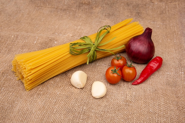 Rauwe Pasta met ingrediënten op linnen of jute zakken of stof