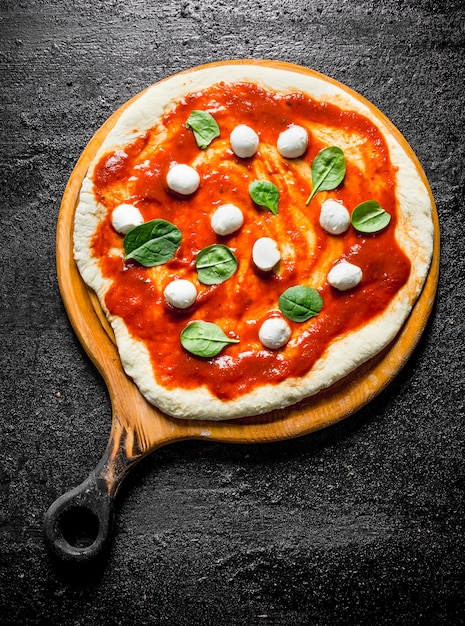 Rauwe pizzadeeg met mozzarella en spinazie