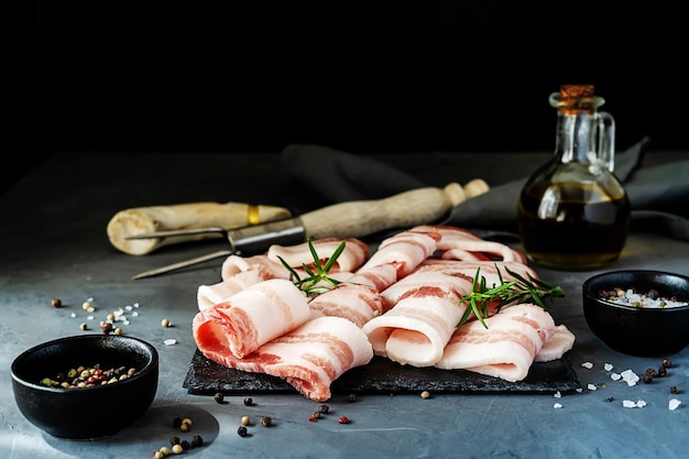 Rauwe plakjes gestreepte spek met specerijen olijfolie en gereedschap voor de grill