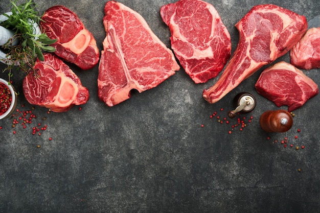 Rauwe prime steaks Verscheidenheid aan verse black angus prime vlees steaks Tbone New York Ribeye Striploin Tomahawk op zwarte of grijze stenen achtergrond Set van verschillende klassieke steaks Bovenaanzicht kopie ruimte