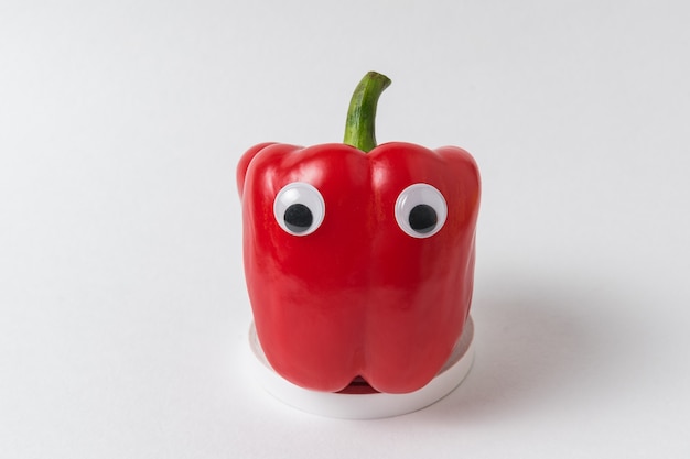 Rauwe rode paprika's met Googly ogen op wit. Peper met grappig gezicht.