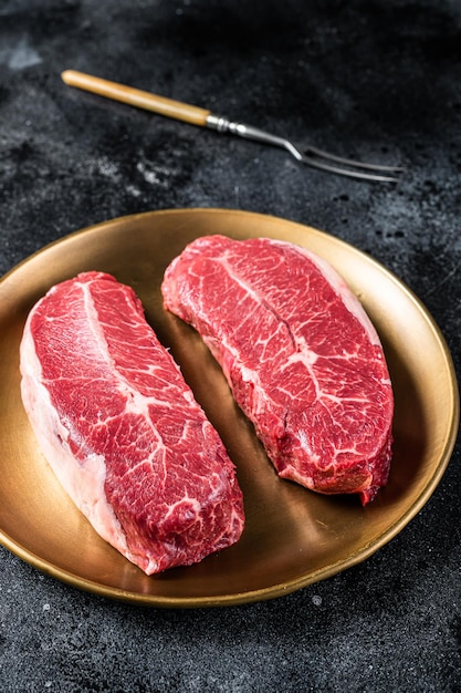 Rauwe schouder Top Blade rundvlees vlees steaks op een plaat zwarte achtergrond bovenaanzicht