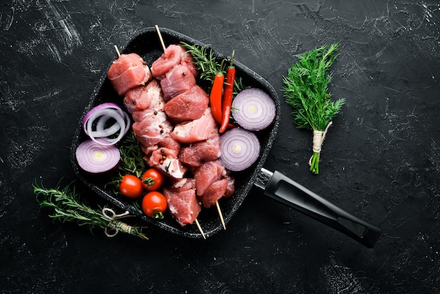 Rauwe shish kebab Barbecue vlees specerijen en kruiden op een zwarte stenen achtergrond Bovenaanzicht Gratis kopieerruimte