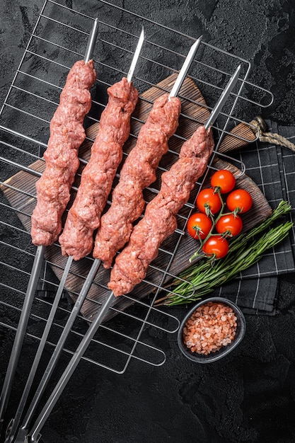 Rauwe shish kebab van gehakt lams- en rundvlees vlees turkse adana kebab op spiesjes zwarte achtergrond top view
