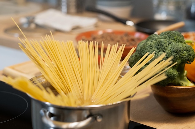 Rauwe spaghetti in metalen pan staande op hete elektrische kookplaat