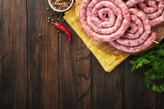 Rauwe spiraalvormige varkensworst Verse varkensworst smakelijke gedraaide spiraal voor bbq op witte standaard met specerijen en kruiden voor Oktoberfest-feestdiner op oude houten achtergrond Bovenaanzicht Oktoberfest-set