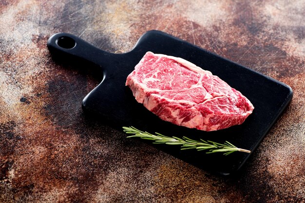 Foto rauwe steak ribeye met rozemarijn en kruiden op een snijplank