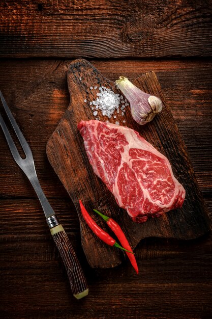 Rauwe steaks op een snijplank met kruiden en knoflook