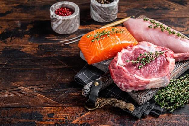 Rauwe steaks vis zalm rundvlees en kalkoenfilet op een snijplank Houten achtergrond Bovenaanzicht Kopieer ruimte