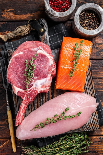 Rauwe steaks - vis, zalm, rundvlees en kalkoenfilet op een snijplank. Houten achtergrond. Bovenaanzicht.