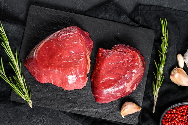 Rauwe steaksfilet mignon bereid om te koken ossenhaas. zwarte muur. bovenaanzicht