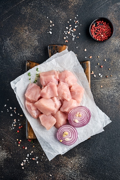 Rauwe stukjes vlees ingrediënten van kip op een houten bord, specerijen, kruiden en groenten