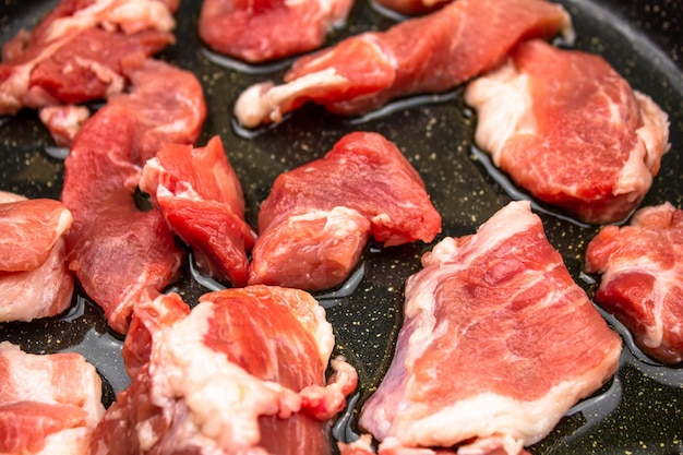Rauwe stukken vlees in een pan Rauwe stukken varkensvlees voor het koken