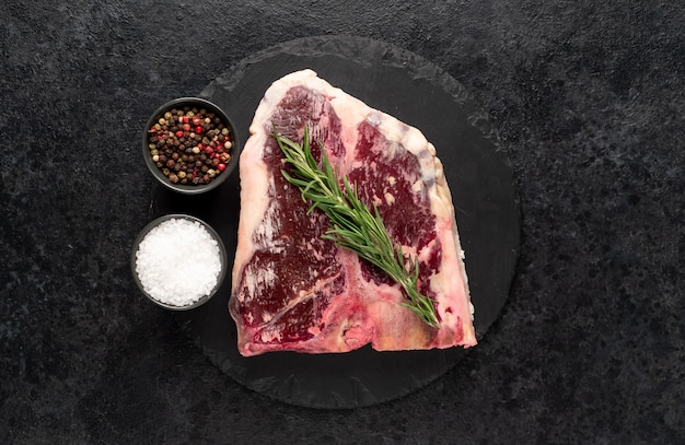 Rauwe tbone steak met kruiden op een stenen achtergrond dryaged steak met kopieerruimte voor uw tekst