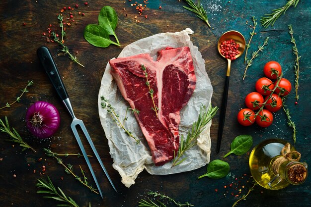 Rauwe Tbone steak op een stenen tafel met tijm, rozemarijn en kruiden Bovenaanzicht Platliggend bovenaanzicht op zwarte stenen snijtafel