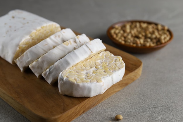 Rauwe tempeh of tempe gemaakt van gefermenteerde sojabonen tempeh plakjes gesneden met mes