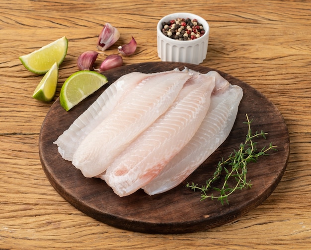 Rauwe tilapia visfilet met kruiden over houten tafel.