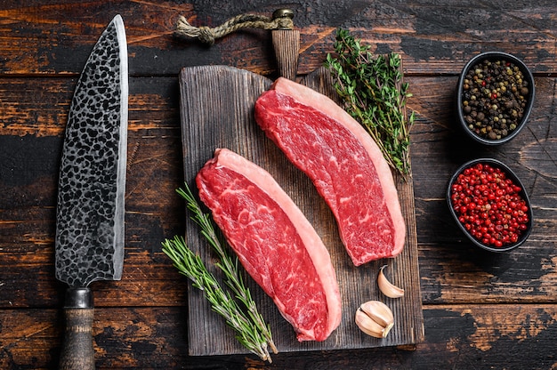 Rauwe top entrecote rundvlees biefstuk op een houten snijplank op houten tafel. Bovenaanzicht.