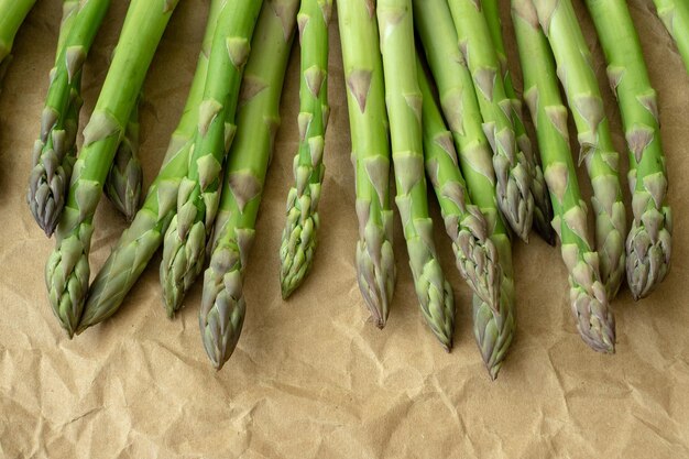 Foto rauwe tuin asparagus stengels verse groene voorjaarsgroenten op bruin verpakkingspapier