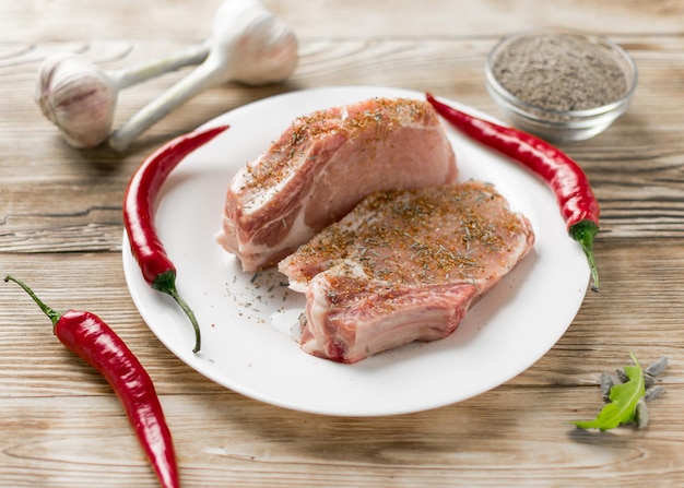 Rauwe varkensribbetjes met rode peper knoflook en kruiden op een houten ondergrond