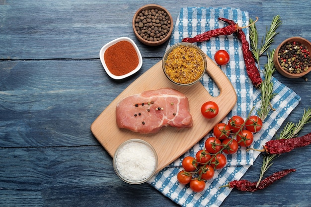 Rauwe varkenssteak op het bord, vlees en ingrediënten om te koken, kruiden, kruiden en groenten op een lichte achtergrond. bovenaanzicht