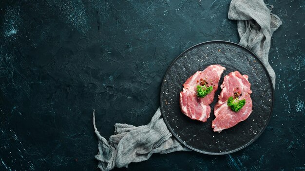 Rauwe varkenssteak Vers vlees Op een bord met kruiden en specerijen Bovenaanzicht Vrije ruimte voor uw tekst