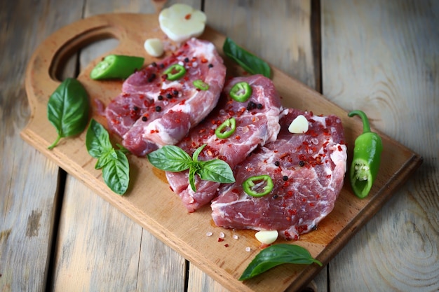 Rauwe varkenssteaks met kruiden op een houten bord