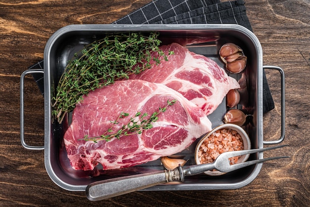 Rauwe varkenssteaks van vers nekvlees in keukenblad met zout en tijm Houten achtergrond Bovenaanzicht
