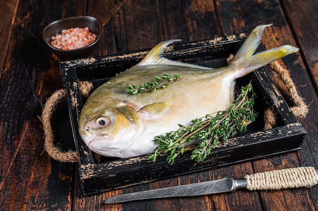 Rauwe vis botervis of pompano met kruiden in een houten bakje