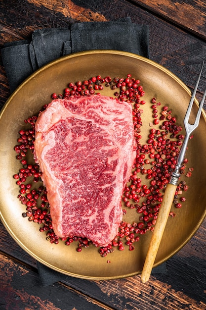 Rauwe Wagyu striploin New York steak op een bord met roze peper Houten achtergrond Bovenaanzicht