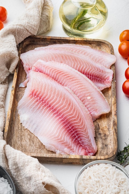 Rauwe witte vis tilapia, met basmatirijst en kerstomaatjes ingrediënten, op witte achtergrond