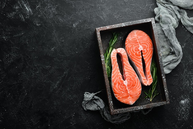 Rauwe zalm steak met ingrediënten op een zwarte achtergrond Bovenaanzicht Vrije ruimte voor uw tekst