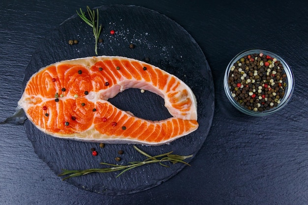 Rauwe zalm steak met kruiden op zwarte leisteen bovenaanzicht