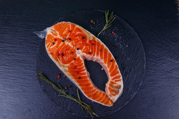 Rauwe zalm steak met kruiden op zwarte leisteen bovenaanzicht