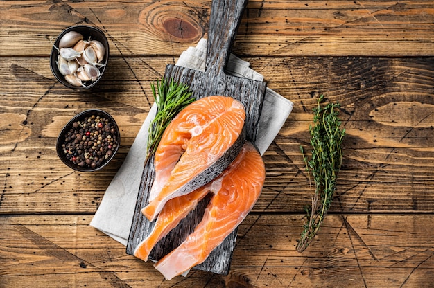 Rauwe zalm steaks op een houten snijplank met tijm en rozemarijn. houten achtergrond. Bovenaanzicht.