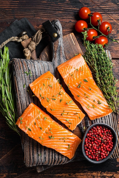 Rauwe zalmfilet steaks op een houten bord met tijm en rozemarijn Houten achtergrond Bovenaanzicht