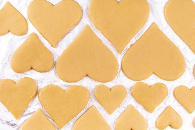 Rauwe, zelfgemaakte hartvormige koekjes liggen op bakfolie en bereiden het voor om naar de oven te worden gestuurd