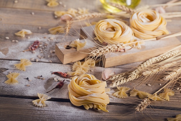 Rauwe zelfgemaakte pasta met bloem en kruiden op de rustieke achtergrond. Ongekookte noedels.