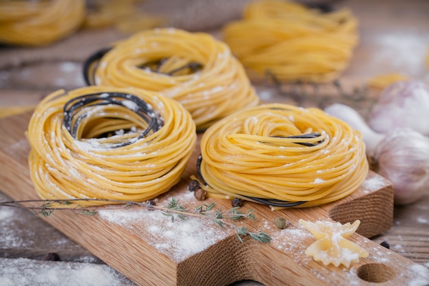 Rauwe zelfgemaakte pasta met bloem, knoflook en kruiden op de rustieke achtergrond. ongekookte noedels.