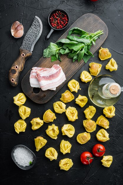 Rauwe zelfgemaakte Tortellini met gezouten ham set, op zwarte tafel, bovenaanzicht plat lag