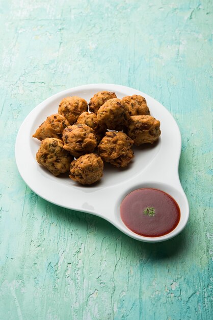 Rava Bhajjまたはbhajiyaは、sujiPakodaまたはsemolinaPakoraとも呼ばれ、トマトケチャップを添えています。セレクティブフォーカス