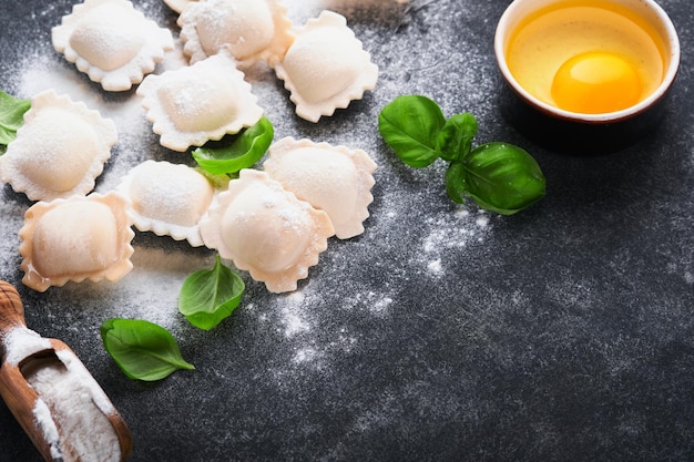 Ravioli Italian food Tasty homemade with flour tomatoes eggs and greens basil on dark background Food cooking ingredients background Top view