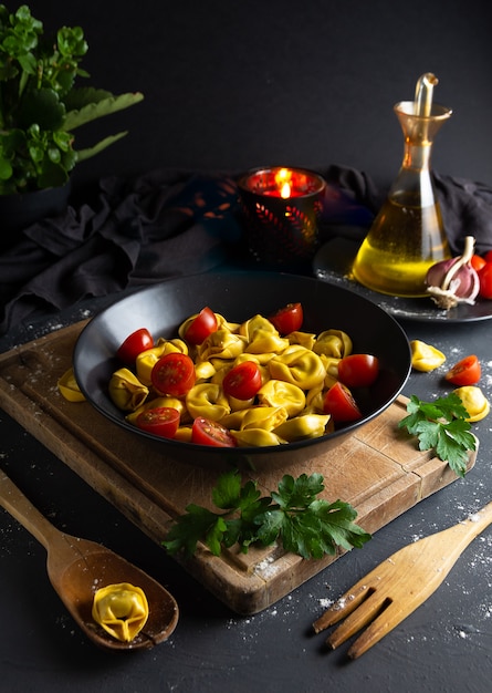 Ravioli met tomaten op zwarte plaat in rustiek eigengemaakt voedselmilieu, luchtmening