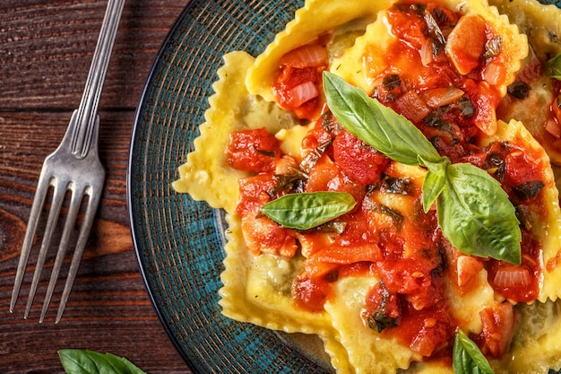 Ravioli met tomatensaus en basilicum op donker