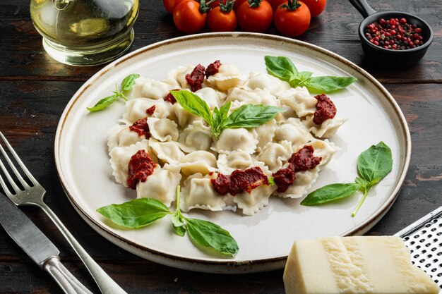 Ravioli pasta with mushroom cream sauce and cheese - Italian food style set with basil parmesan and tomatoe  on white plate  on old dark  wooden table background