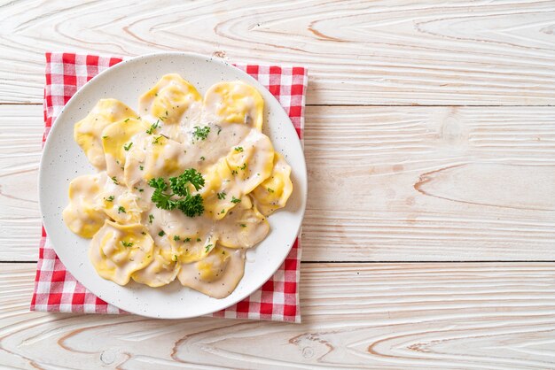 Foto ravioli con salsa di crema di funghi e formaggio - stile di cibo italiano