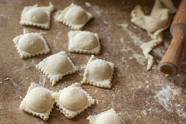 Ravioli raw dough filling square dumplings on the table healthy meal copy space food background