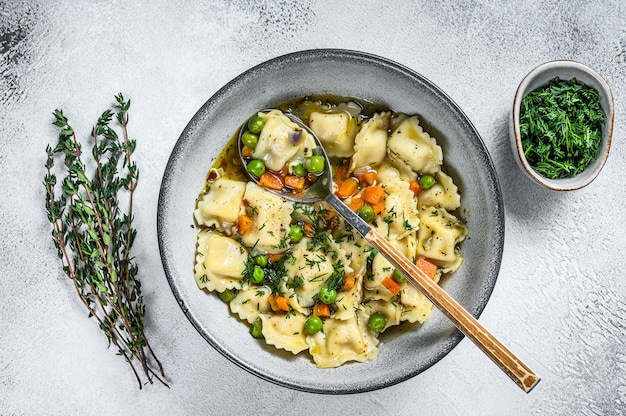 Ravioli Soep dumplings pasta in een kom met greens. Witte achtergrond. Bovenaanzicht.