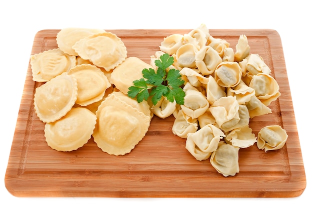 Ravioli and tortellini on wood board